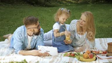 快乐女孩和<strong>爸爸妈妈</strong>在阳光明媚的夏日草地上玩得开心的家庭画像